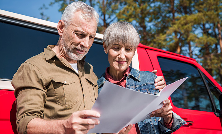 Una pareja de adultos mayores buscando su próximo destino en el mapa