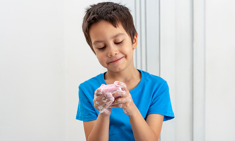 NIño lavándose las manos para el cuidado personal