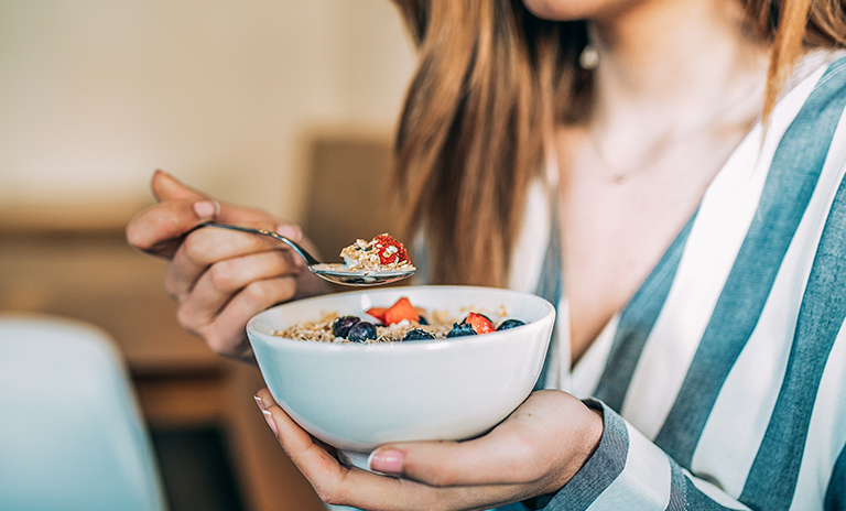 Mujer desayunando frutas y yogur