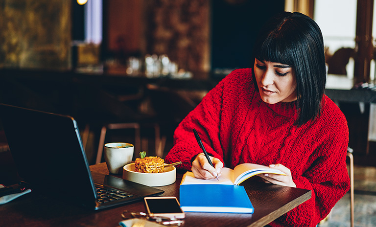 Mujer escribiendo anotaciones de los cursos gratis para hacer en cuarentena