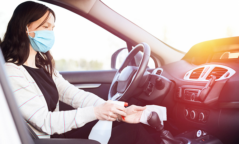 Mujer limpiando el carro como parte de las recomendaciones para viajar por carretera en diciembre