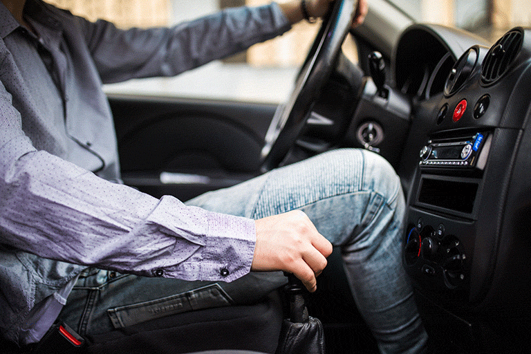 hombre dentro de un carro, tomando el volante y los cambios