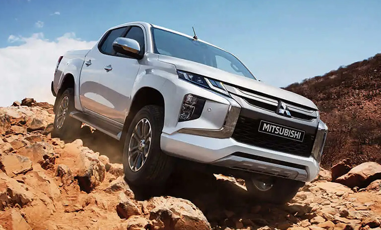 camioneta con platón sobre una montaña con piedras grandes. Es el modelo de L22 de Mitsubishi