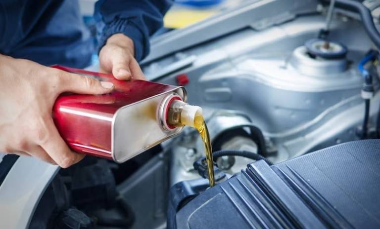 Persona vertiendo aceite en el motor de su carro