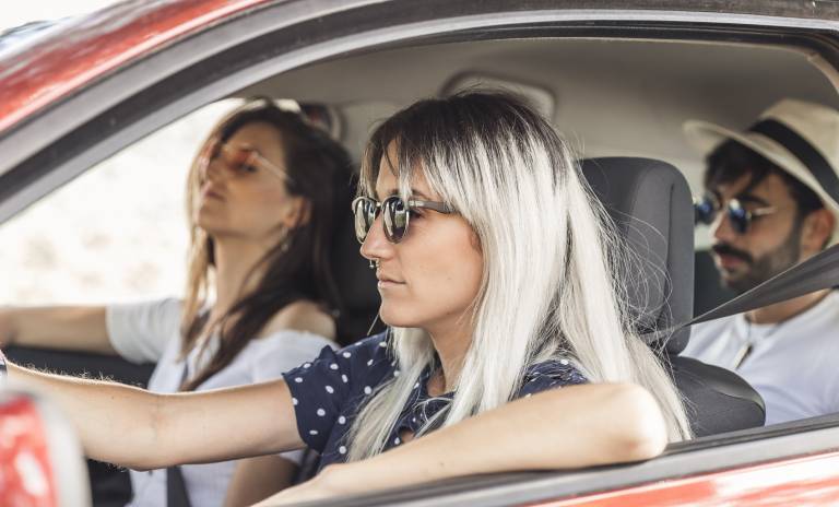 Tres personas están en un carro mirando hacia el frente