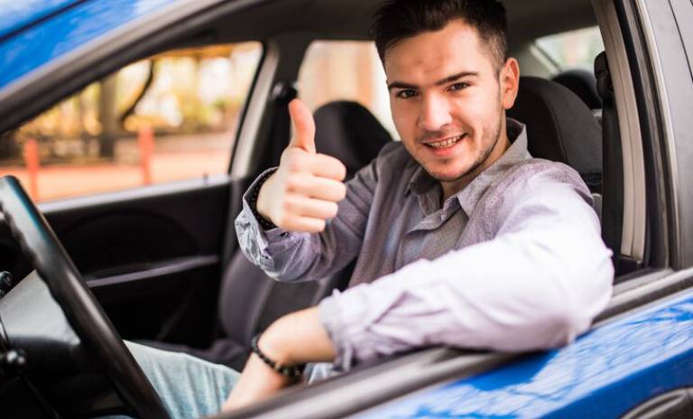 Hombre con el pulgar arriba dentro de su carro.