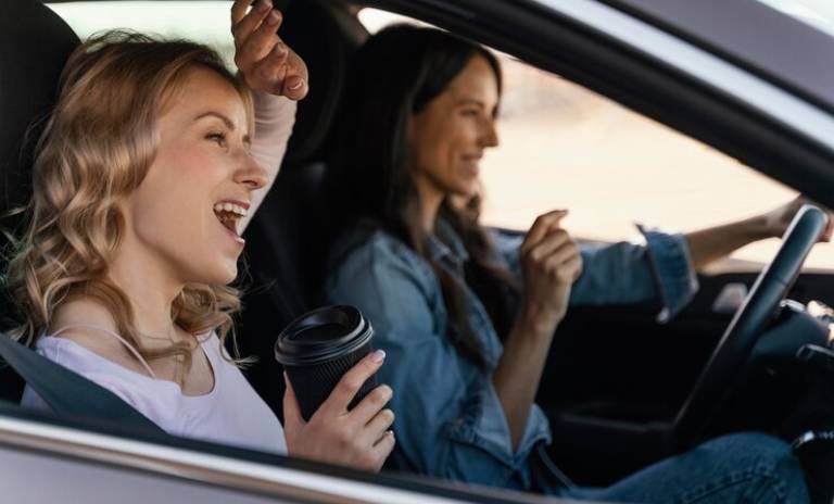 Dos mujeres dentro de un carro felices.