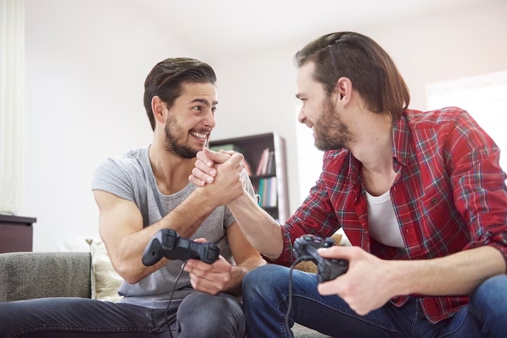 Dos personas dándose la mano en una sala mientras sostienen controles de videojuego.