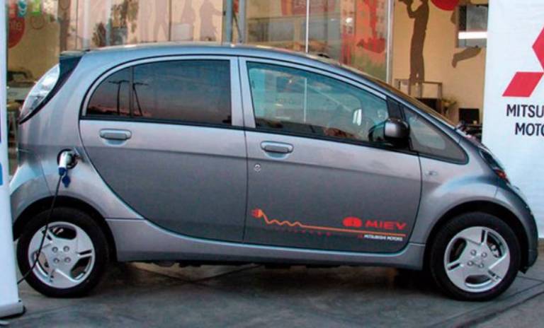 Auto tecnológico de cuatro puertas en estación de carga para vehículos híbridos.