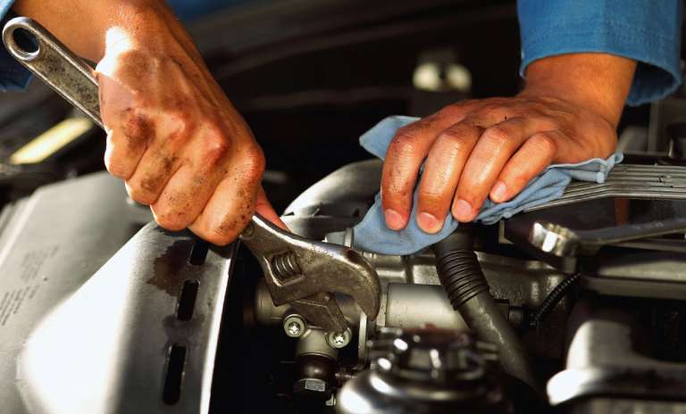 Unas manos haciendo un arreglo en el motor del vehículo