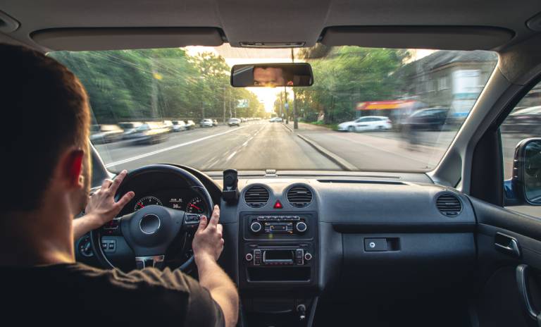 Conductor con las manos en el volante manejando a alta velocidad desde el interior del coche.